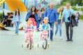 two little girls ride on 4 wheeled bicycles on the Volga river embankment on a summer sunny day Royalty Free Stock Photo