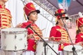 beautiful girls in a hussar uniform play drums at a carnival procession at a flower festival in a city park on a summer day