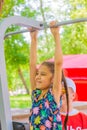 A girl passes the standards for pulling up on a horizontal bar in the park sunny day