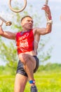 A young athlete, a participant in the race of heroes, overcomes the track on the rings. Text in Russian: race of heroes, champions