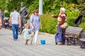 A beggarly elderly woman asks for alms on the embankment near a sculpture to Red Army soldier Sukhov Royalty Free Stock Photo