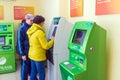 Mature beautiful woman pays utilities through an ATM. Text in Russian: Sberbank, ATM