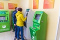 Mature beautiful woman pays utilities through an ATM. Text in Russian: Sberbank, ATM