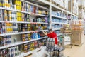 A store employee with the inscription on the back `Always happy to help you` near the shelves with drinks.