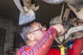 a male auto mechanic repairs a car suspension on a lift