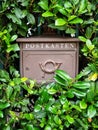 Russia, Sochi 10.03.2019. Brown iron letterbox with an inscription and a pattern in green bushes