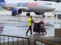 Russia, Sochi 02.11.2021. A cleaning lady in a yellow vest with a cart and equipment walks along the airfield past the