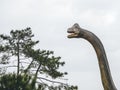 Russia, Sochi 14.03.2020. Dinosaur brachiosaurus statue head with a long neck next to a tree against the sky Royalty Free Stock Photo