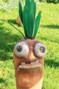 Russia, Sochi 14.05.2022. Funny carrot with bulging eyes on the background of a green lawn. Garden cartoon figurine in