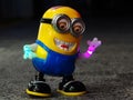 Russia, Sochi 31.05.2021. A funny plastic toy minion with glowing hands stands in a pose on the night square