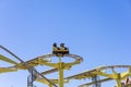 Russia, Sochi 14.05.2022. People in a yellow open trailer ride on an attraction against a blue sky. Extreme attraction