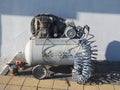 Russia, Sochi 01.05.2021. The piston compressor sits outside on the paving slabs against the white wall. Painting works