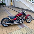 Russia, Sochi 15.02.2021. A red-black glossy motorcycle with silver chrome details is parked at the curb on a sidewalk Royalty Free Stock Photo