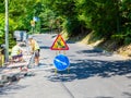 Russia, Sochi 29.06.2020. The road with signs standing on it and workers laying out paving tiles. Roadworks