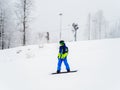 Russia, Sochi 21.01.2020. Snowboarder in a blue suit is driving along the track in foggy weather