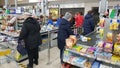 Customers in the checkout area and signs marking the distance to the floor in the supermarket during the coronavirus epidemic