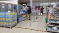 Customers in the checkout area and signs marking the distance to the floor in the supermarket during the coronavirus epidemic