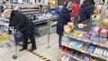 Customers in the checkout area and signs marking the distance to the floor in the supermarket during the coronavirus epidemic