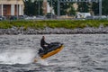 Russia, St. Petersburg, 29 July 2022: a man in a wetsuit rides a jet ski in sunny weather, jumps and has fun, splashes Royalty Free Stock Photo