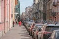 Russia, St. Petersburg, a narrow street, a dense row of cars, expressive architecture in pink tones, the silhouette of a girl in a