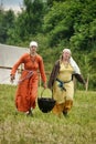 Women in Viking clothes carry a cauldron with food at the historical reconstruction