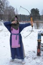 A girl shoots in the winter from a bow at the festival of medieval Vikings