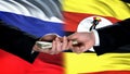 Russia and Uganda officials exchanging money, flag background, business deal