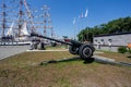 Russia, Vladivostok, 07/28/2018. Modern cannon on the navy pier of Russian Pacific Fleet. Moored sailing ships