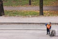 Russia, Vladivostok October 21, 2020: A road worker in an orange vest removes old asphalt with a shovel. Road works to replace