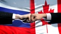 Russia vs Canada conflict, international relations, fists on flag background Royalty Free Stock Photo