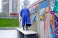 Russia, Yekaterinburg, August 14, 2019 a man in a raincoat washes away graffiti on the city wall with a stream of water and