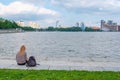 Russia, Yekaterinburg, August 14, 2019 a single girl is sitting resting on the embankment of a river flowing in a large city near