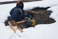 Russia, Yekaterinburg. A group of people eliminate the accident of water supply. Pumped water from the well. Snow