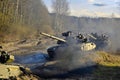 Russian armored combat vehicles are navigating through marshland through forests.