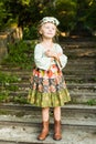 Russian beauty girl in folk costume stands on the steps in the woods on a summer day