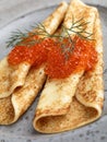 Russian Blinis with red caviar on a gray plate closeup