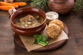 Russian cabbage soup shchi with pork and cabbage in clay pot and bread bun on wooden table Royalty Free Stock Photo