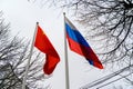 Russian and Chinese flags are flying in the wind. Flags of Russia and China on flagpoles