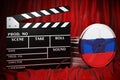 Russian cinematography, film industry, cinema in Russia. Clapperboard with and film reels on the red fabric, 3D rendering