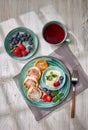 Russian cottage cheese pancakes Syrniki with berries and sour cream on light wooden background. Top view. Healthy breakfast