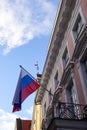 Russian flag, bottom up view to yellow and pink buildings facades. Weather vane on the roof. Blue sky with white clouds Royalty Free Stock Photo