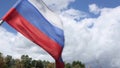 Russian flag waving from wind against green trees and city flashlights