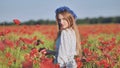 A Russian girl with a blue wreath of cornflowers poses in a field of poppies.