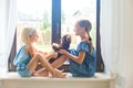 Russian girls sitting near window at home playing teddy bear