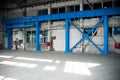 Manufacturing factory. Empty hangar building. Blue toned background. The production room with large windows and metal structures