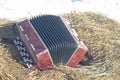 The Russian musical traditional instrument bayan lies on the hay on the Maslenitsa holiday