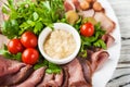 Russian national cuisine. Marinated tomatoes, chopped meat, olives, parsley. Horseradish sauce. Salad closeup on a plate. Royalty Free Stock Photo