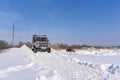 Russian offroad SUV `UAZ hunter 469` 4x4 rides on a snowy mountain in winter in a field on a bad road
