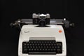 Russian old Zenit E film camera on vintage white Olympia Arabic typewriter. Royalty Free Stock Photo