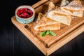 Pancakes with sugar powder and jam on a wooden board. Dark table, empty space. Maslenitsa, russian carnival